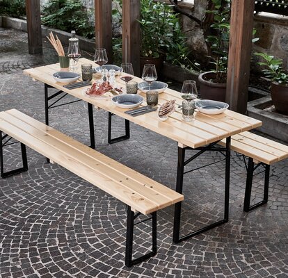 The "SitDown" beer table set is in the shade on the terrace. The table is beautifully set with blue plates, wine glasses and small dishes.