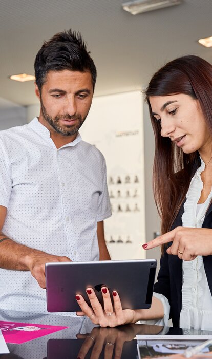 Die Frau erklärt am Tablet dem Kunden alle Details im Verkaufsgespräch.