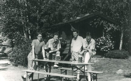 Vier Männer stehen um eine Bierzeltgarnitur und vier Bierkrüge stehen auf der Garnitur