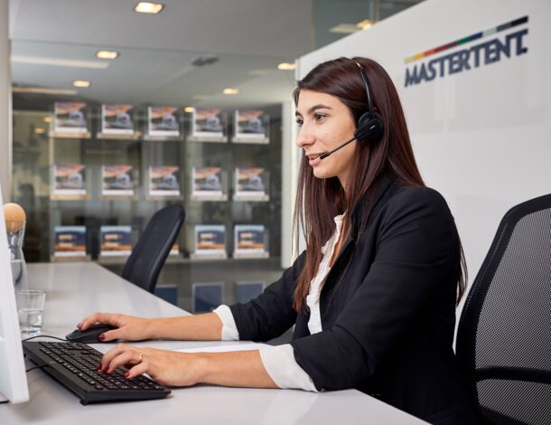 Eine Mitarbeiterin sitzt mit einem Headset vor dem PC und betreut den Kunden am Telefon.