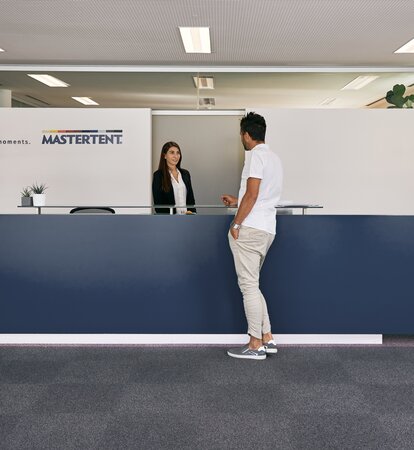The receptionist welcomes the customer in the entrance area of the MASTERTENT headquarters.