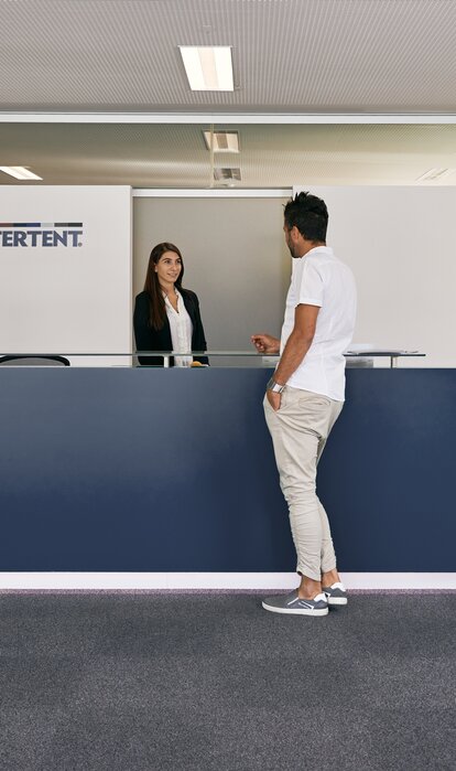 The receptionist welcomes the customer in the entrance area of the MASTERTENT headquarters.