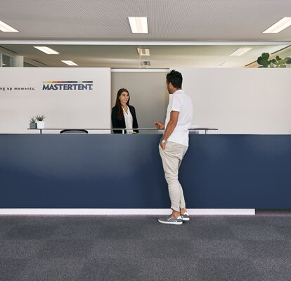 The receptionist welcomes the customer in the entrance area of the MASTERTENT headquarters.