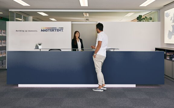 La signora alla reception accoglie il cliente nella zona d´ingresso nella sede centrale di MASTERTENT.