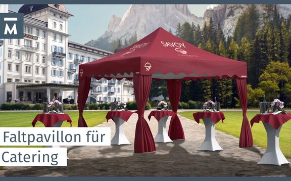 Roter eleganter Faltpavillon mit gewellter Blende und Eckvorhängen steht vor einem Hotel im Garten. Darunter befinden sich Stehtische.