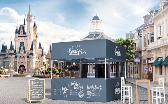 Blauer Faltpavillon mit Flachdach als Burgerstand auf einem Platz. Dahinter befindet sich eine Kirche.