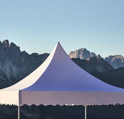 Il tetto bianco del gazebo pagoda con il frontalino ondulato. Nello sfondo si vedono le montagne.