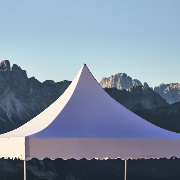 Il tetto bianco del gazebo pagoda con il frontalino ondulato. Nello sfondo si vedono le montagne.