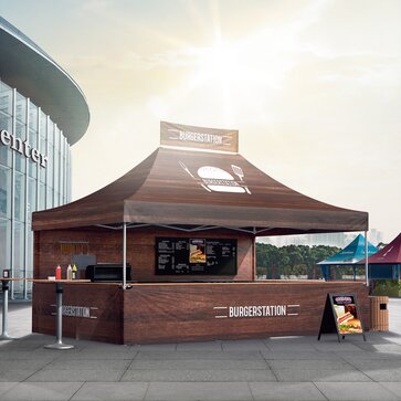 Brown gazebo with full-surface printing serving as a burger stand. It is located in front of a trade fair. 