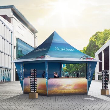 Das Promotionzelt für Sonnenbrillen steht in der Einkaufsstraße. Der Faltpavillon ist und blau und vollflächig bedruckt. 