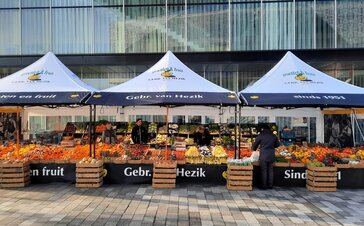 Für den Obstmarkt stehen drei Faltzelte von Gebr. van Hezik mit vollflächiger Bedruckung, Vordächern und schwarzer Struktur auf dem Obstmarkt.