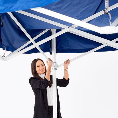 Femeia fixează acoperișul pavilionului albastru pliabil la locul lui.