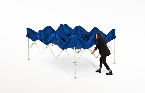 Frau zieht die Struktur des blauen Faltpavillons auseinander.