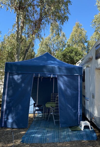 Blue camping tent with blue side walls serves as caravan awning.