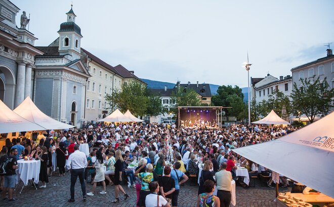 Több rendezvénypavilon a brixeni Dóm téren a Dine & Wine Fesztiválon. Az emberek ülnek és ünnepelnek.