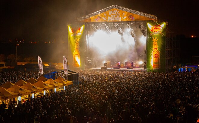 Yellow event tents are standing in front of a stage at a concert. Next to it are bannders from the brand Desperados