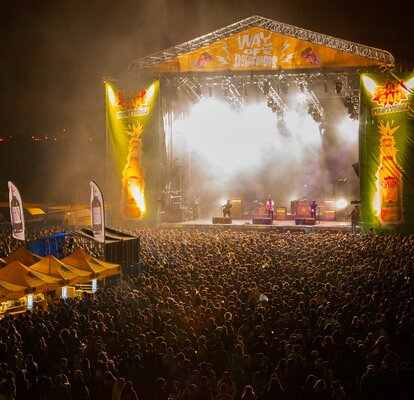 Yellow event tents are standing in front of a stage at a concert. Next to it are bannders from the brand Desperados