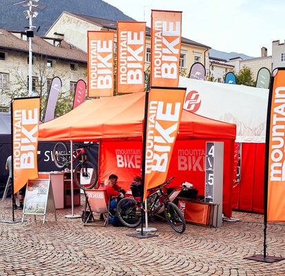 Promotional orange folding gazebo 4.5x3 m Mountainbike with flags and orange side wall customised with logo. 