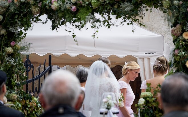 Die Braut und Ihre Gäste stehen vor dem MASTERTENT Faltpavillon und reden miteinander.