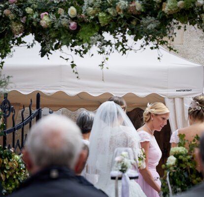 La sposa e i suoi ospitit si trovano di fronte al gazebo pieghevole e parlano.