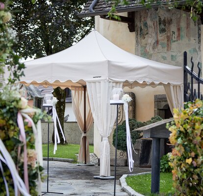 Gazebo pieghevole nuziale color ecru si trova davanti ad una chiesa. Ha il frontalino ondulato e i copripalo.