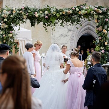 Eleganter Faltpavillon von Mastertent für eine Hochzeit. Man sieht die Braut von hinten zur Kirche kommen.