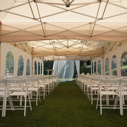 The pagoda tent in ecru used as a wedding tent. The gazebo is equipped with chairs. 