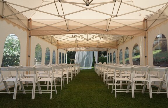 The pagoda tent in ecru used as a wedding tent. The gazebo is equipped with chairs. 