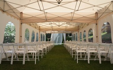 Das Pagodenzelt in ecru im Einsatz als Hochzeitszelt. Der Faltpavillon ist mit Stühlen ausgestattet und feierlich vorbereitet.