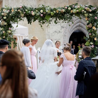 Eleganter Faltpavillon von Mastertent für eine Hochzeit. Man sieht die Braut von hinten zur Kirche kommen.