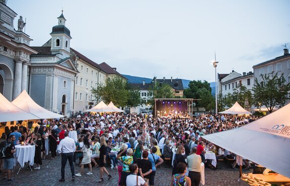 Several gazebos on the Brixen Dome Square at the Dine & Wine Festival. People are sitting and celebrating.
