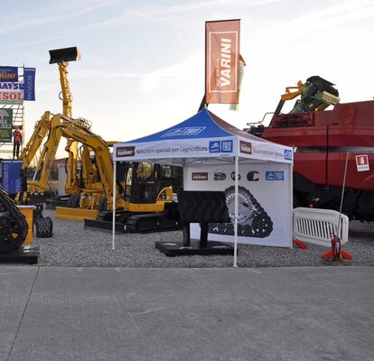 Gazebo pieghevole di Varini su una fiera outdoor. Il gazebo è personalizzato. Vicino si trova una ruspa e qualche macchinario