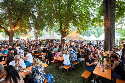 Gazebo pieghevoli allo Street Food Festival di Bressanone. I visitatori passeggiano tra gli stand, gustando cibo e bevande.
