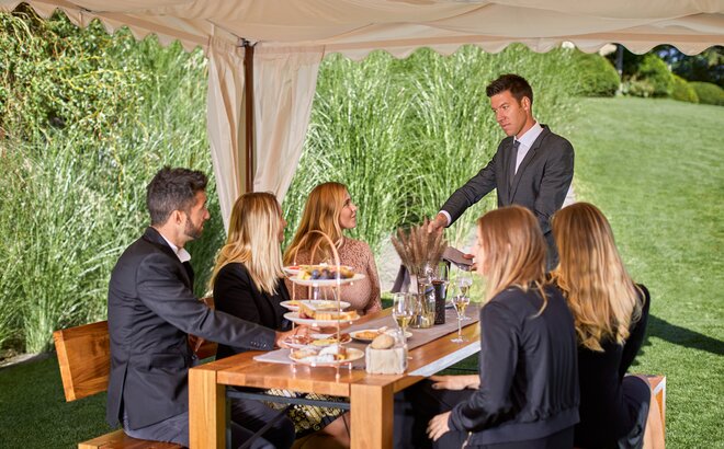 People eat under the tent in the garden.