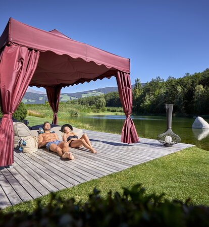 Das Kit Royal in bordeaux steht am See. Ein Paar sonnt sich darunter.