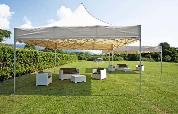 Two 5x5 m gazebos are placed in the garden. There are seating areas under them.