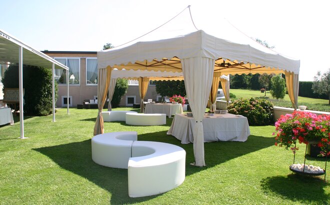 Elegant gazebo with corner curtains for an outdoor party. Underneath a beer table set is located. 