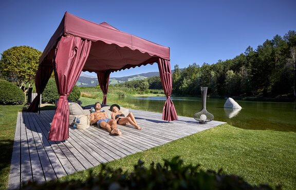 Das Kit Royal in bordeaux steht am See. Ein Paar sonnt sich darunter.