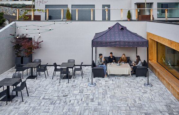 Bedrucktes Raucherzelt steht vor dem Restaurant. Die vier Personen darunter rauchen.