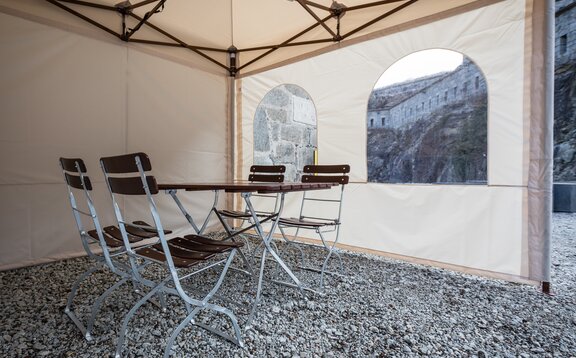 Gazebo pieghevole dall´interno con pareti laterali Il gazebo pieghevole visto dall´interno. Ci sono un tavolo e due sedie all´interno della tenda. Si vede la parete laterale con finestra.