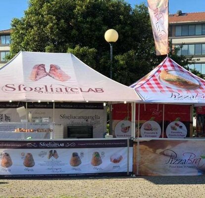 Due gazbo pieghevoli per street food con tettoia e bandiera sul tetto. Entrambi i gazebo pieghevoli sono completamente personalizzati.