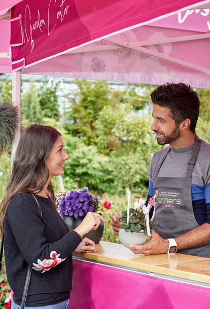 Un cliente sta parlando con un commesso della giardineria sotto ad un gazebo rosa con tettoia