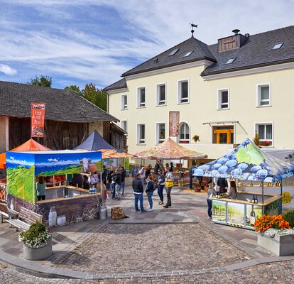 Various market tents on the market place. Every seller has his own gazebo, in between customers and buyers are circulating. 