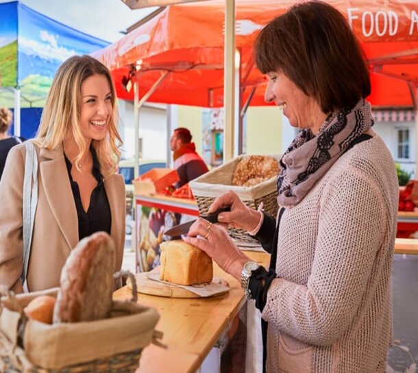 Marktzelt bedruckt eines Bäckers zeigt zwei Frauen beim Verkaufsgespräch.