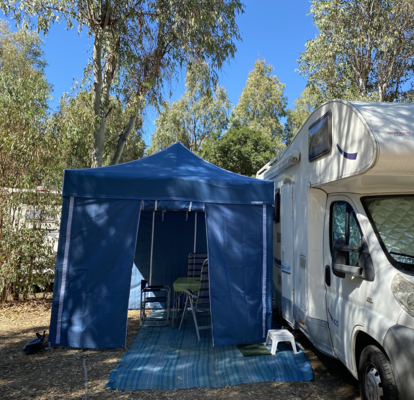Blue camping tent with blue side walls serves as caravan awning.