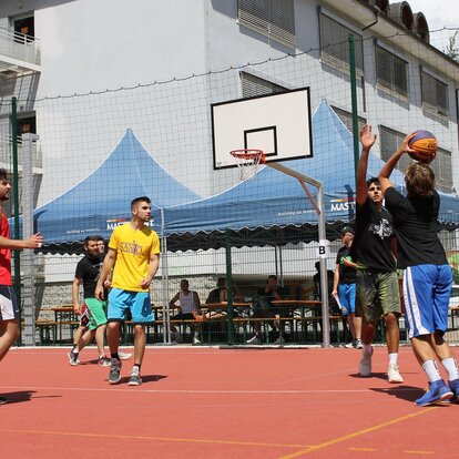 Der ragazzi giocano a basket, dietro si vedono alcuni gazebo pieghevoli MASTERTENT.