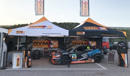 Fully personalised racing tent at a road event. It is fully printed. Underneath is a car. The racing team belongs to Rymax.