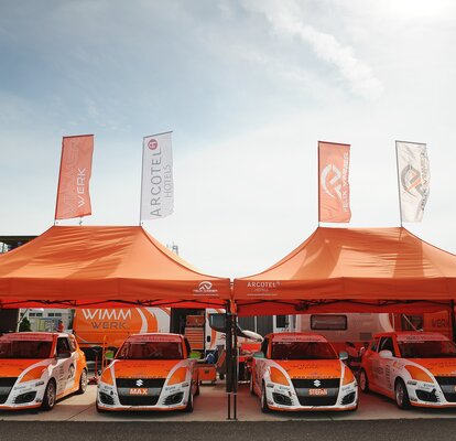  Orange 8x4 gazebo with black frame and two customised flags with Wimmer Werk logo. Paddock gazebo for rally racing cars.