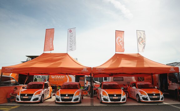  Orange 8x4 gazebo with black frame and two customised flags with Wimmer Werk logo. Paddock gazebo for rally racing cars.