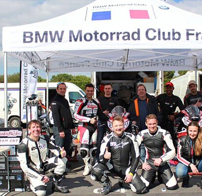 Weißes Rennzelt mit der Aufschrift "BMW Motorrad Club France". Darunter hockt das Rennteam.